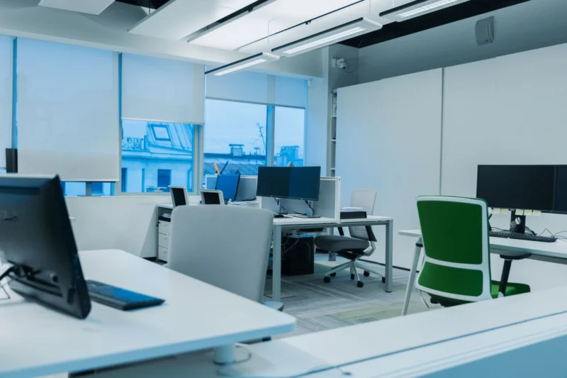 Open-plan office with computer screens near large windows